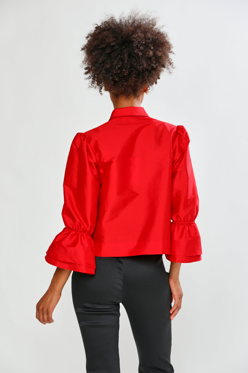 Person wearing a red blouse with puffed sleeves on a white background