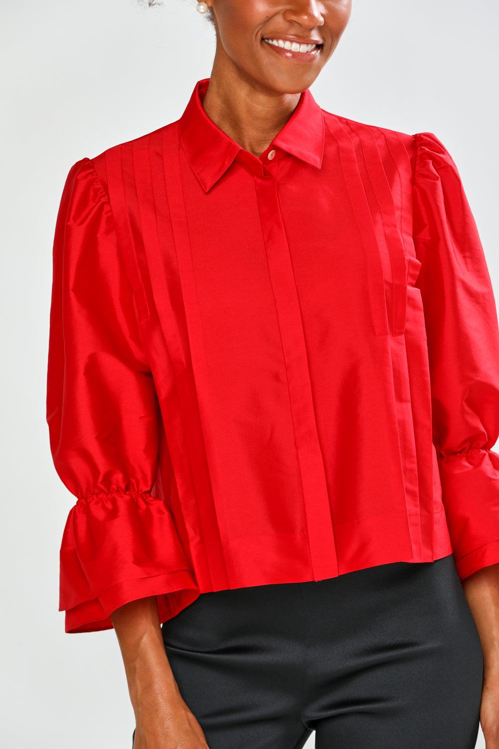 Person wearing a red blouse with puff sleeves on a white background