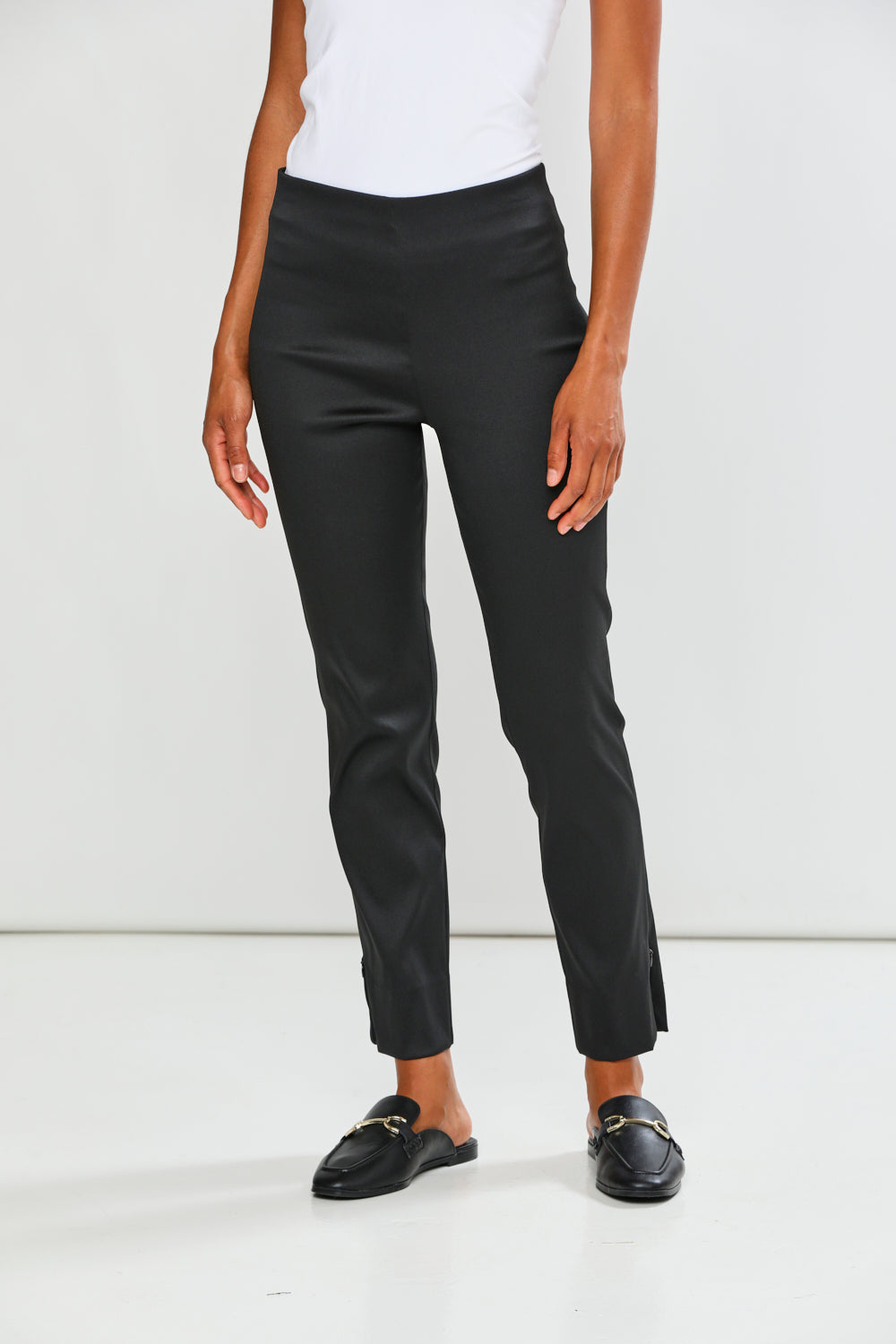Person wearing black pants and black loafers on a white background