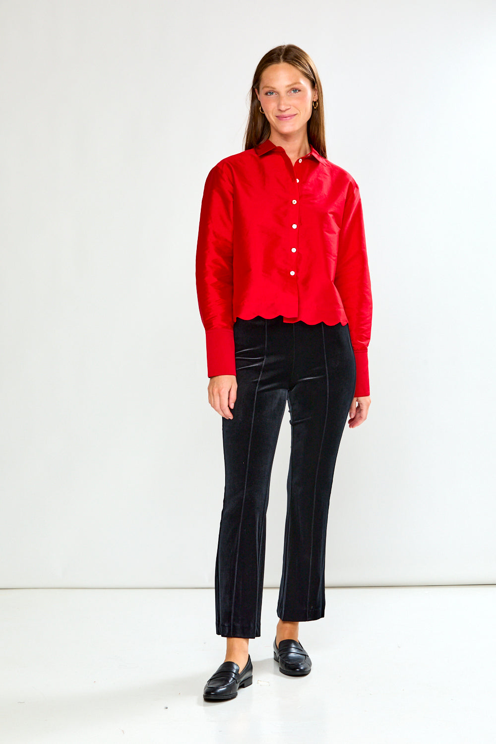 Woman wearing a red blouse and black pants on a white background
