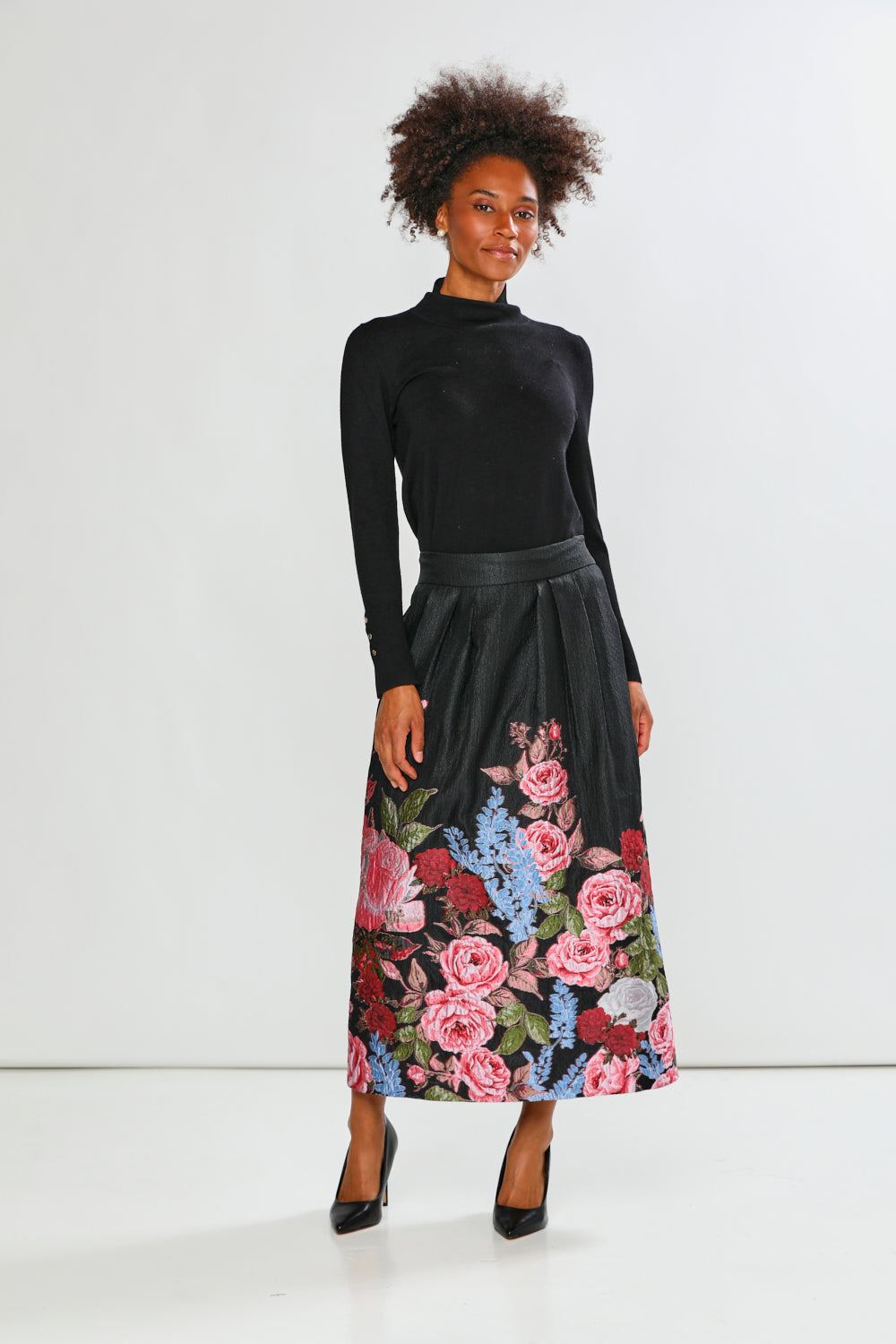 Woman wearing a black top and floral skirt on a white background