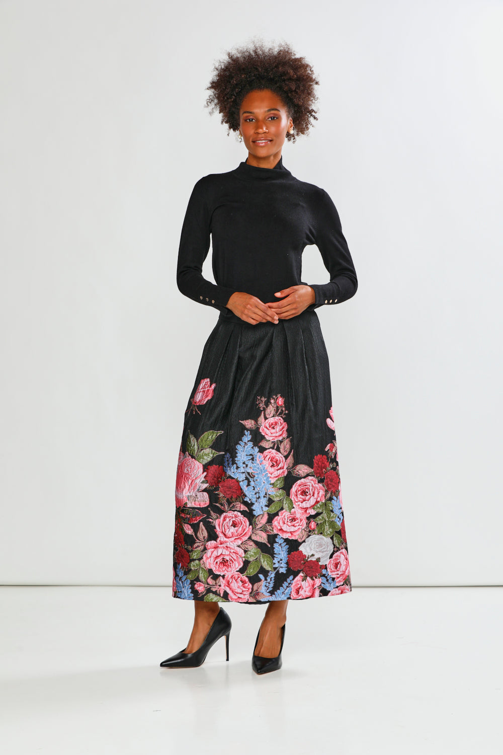 Woman wearing a black top and floral skirt on a white background