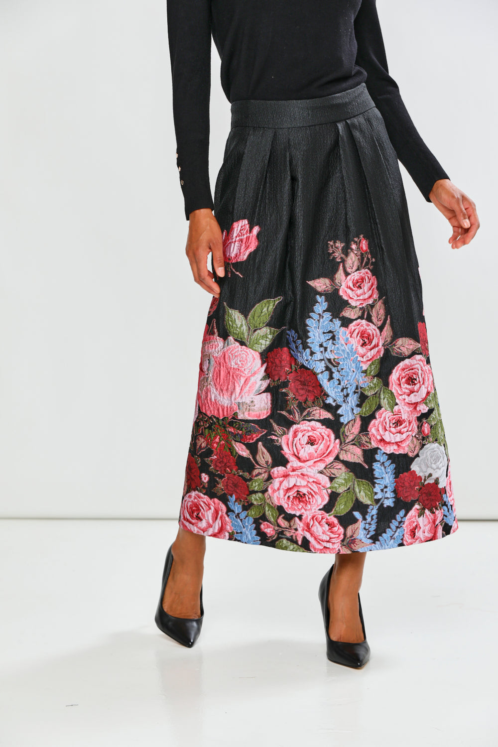 Woman wearing a black top and floral skirt on a white background