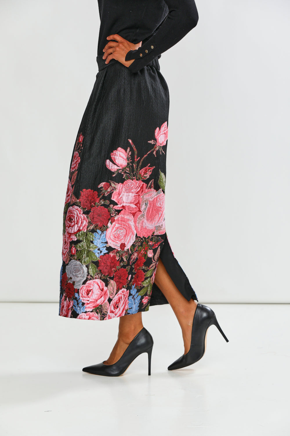 Woman wearing a black top and floral skirt on a white background