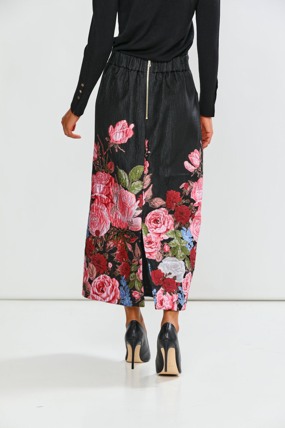 Woman wearing a black top and floral skirt on a white background