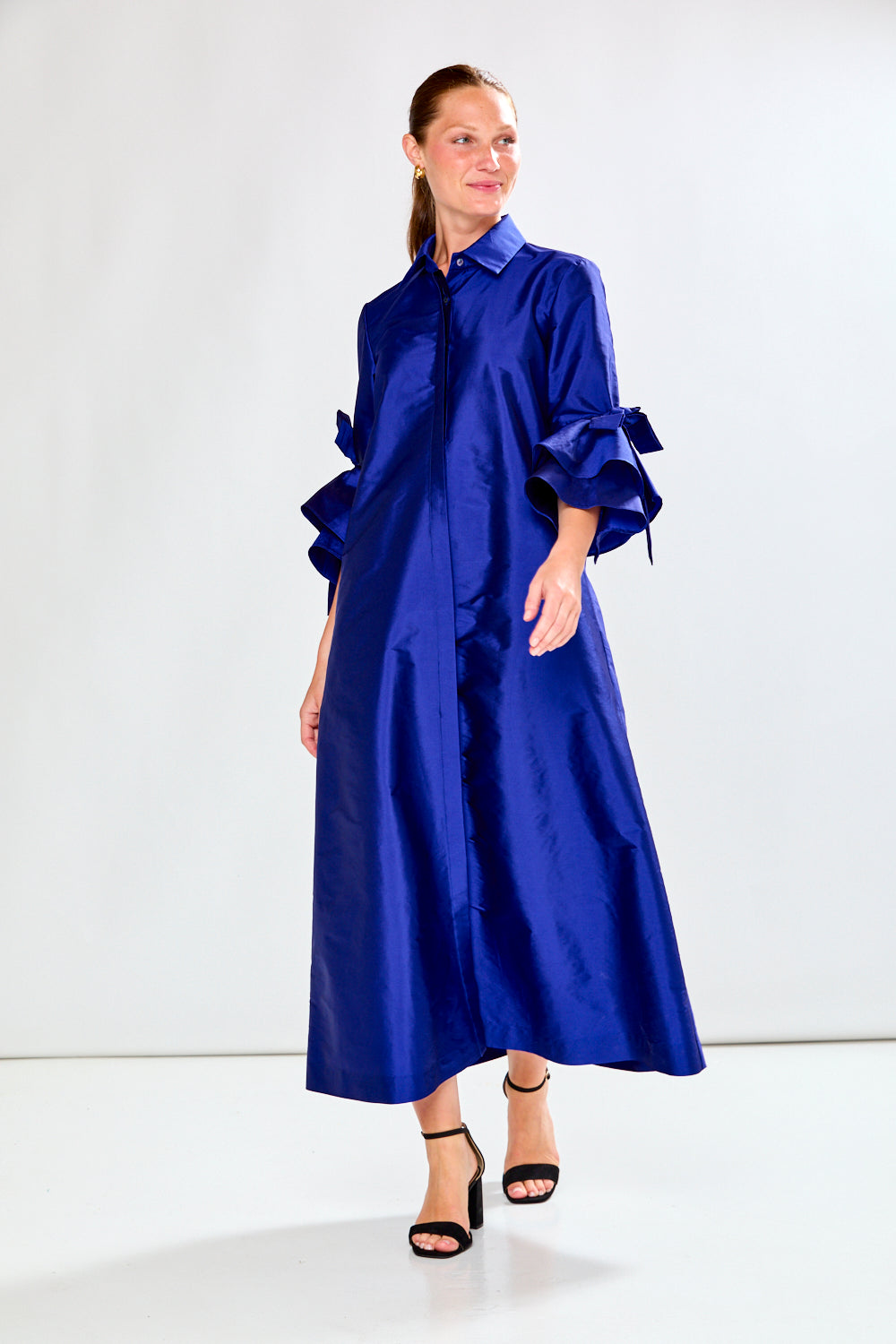 Woman wearing a long blue dress against a white background