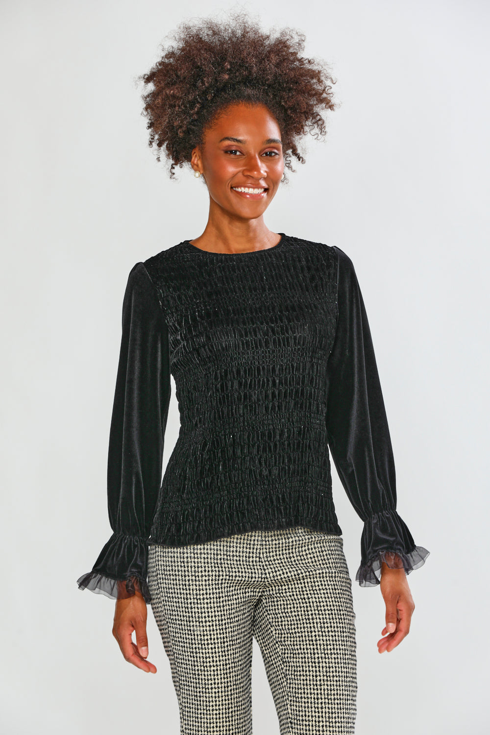 Woman wearing a black textured top with ruffled sleeves on a white background