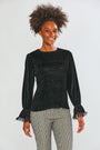 Woman wearing a black textured top with ruffled sleeves on a white background