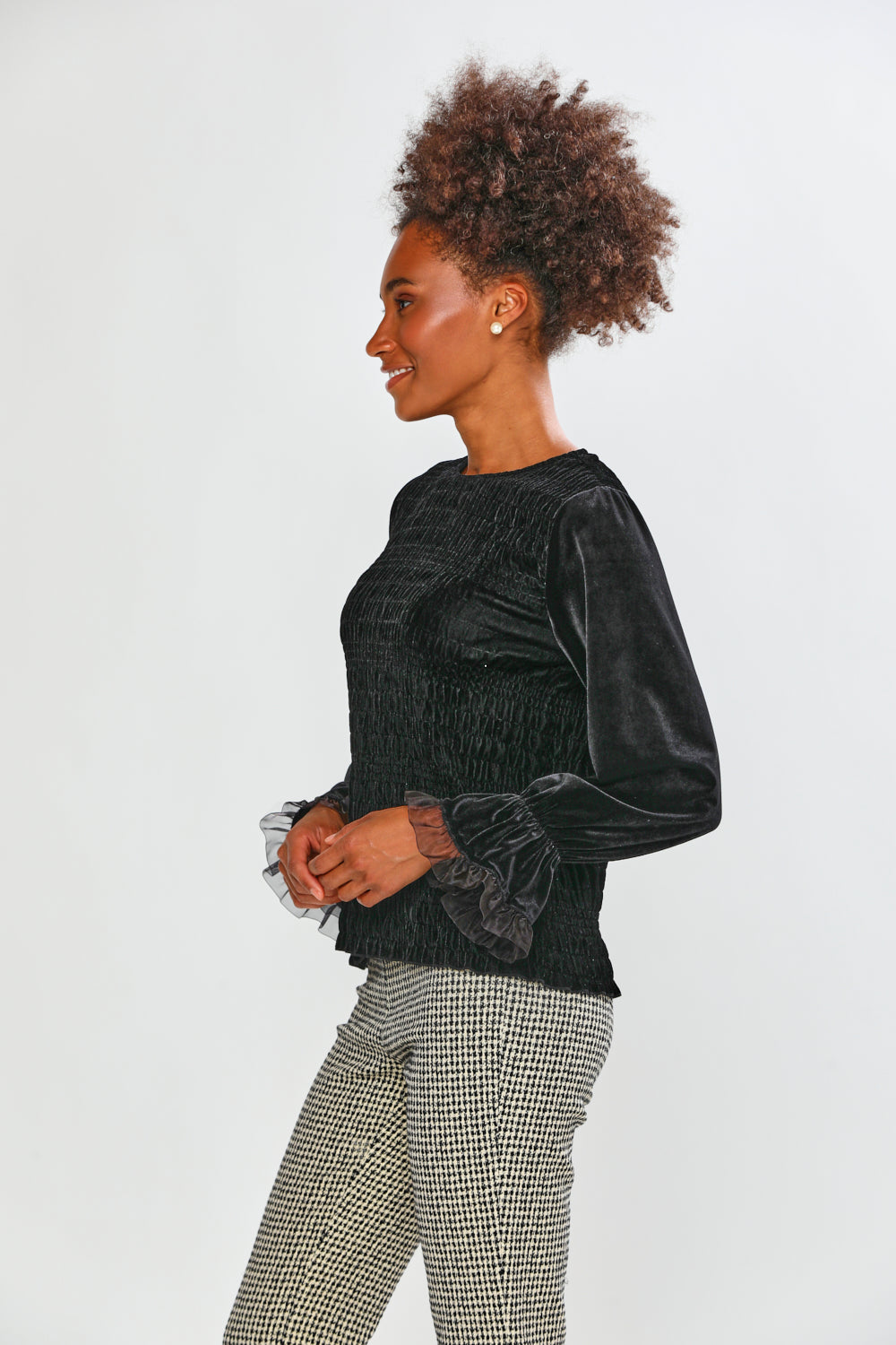 Woman wearing a black velvet top and checkered pants on a white background