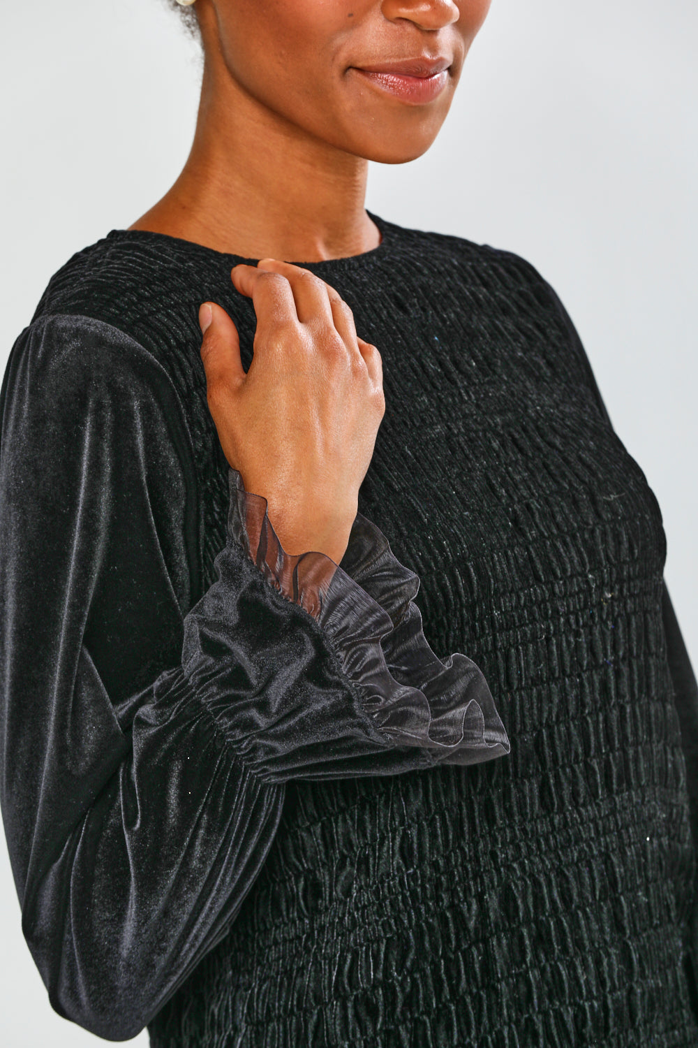 Person wearing a textured black dress with long sleeves on a plain background