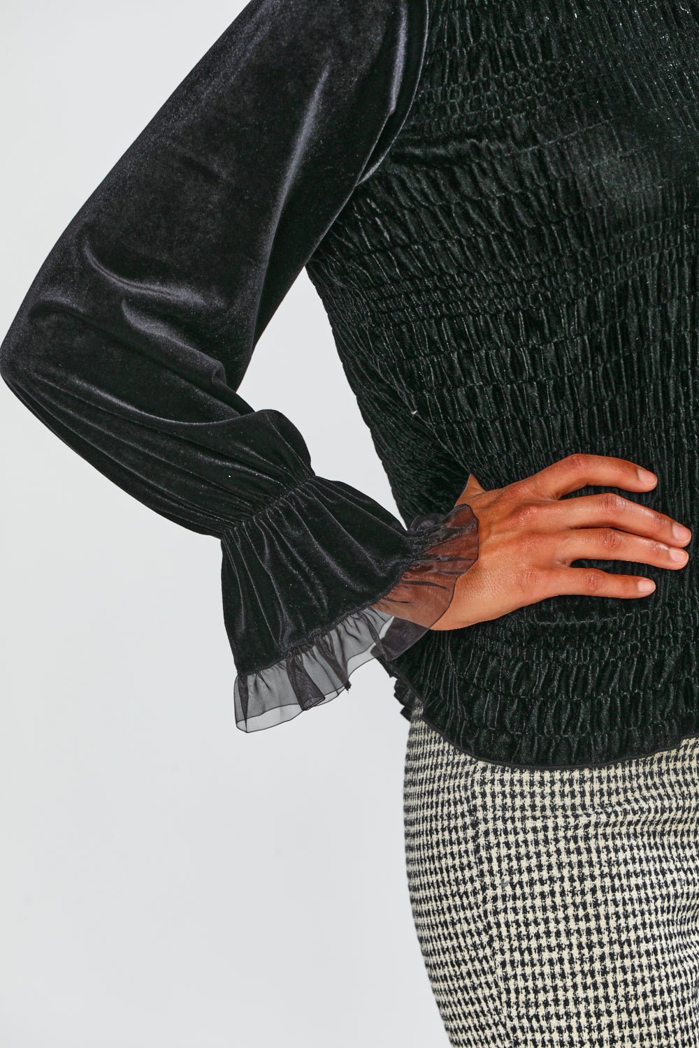 Black textured sweater with sheer sleeves worn by a person on a light gray background