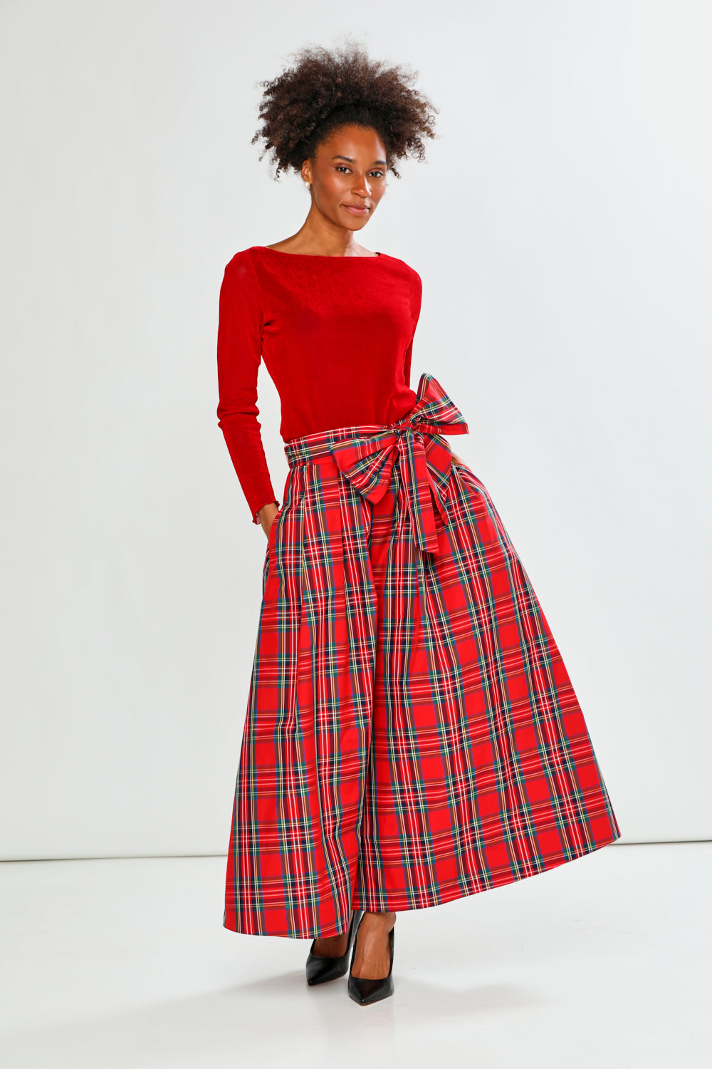 Woman wearing a red top and plaid skirt on a white background