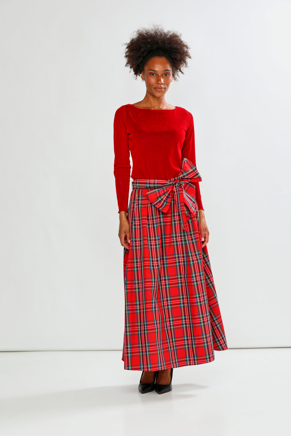 Woman wearing a red sweater and plaid skirt on a white background