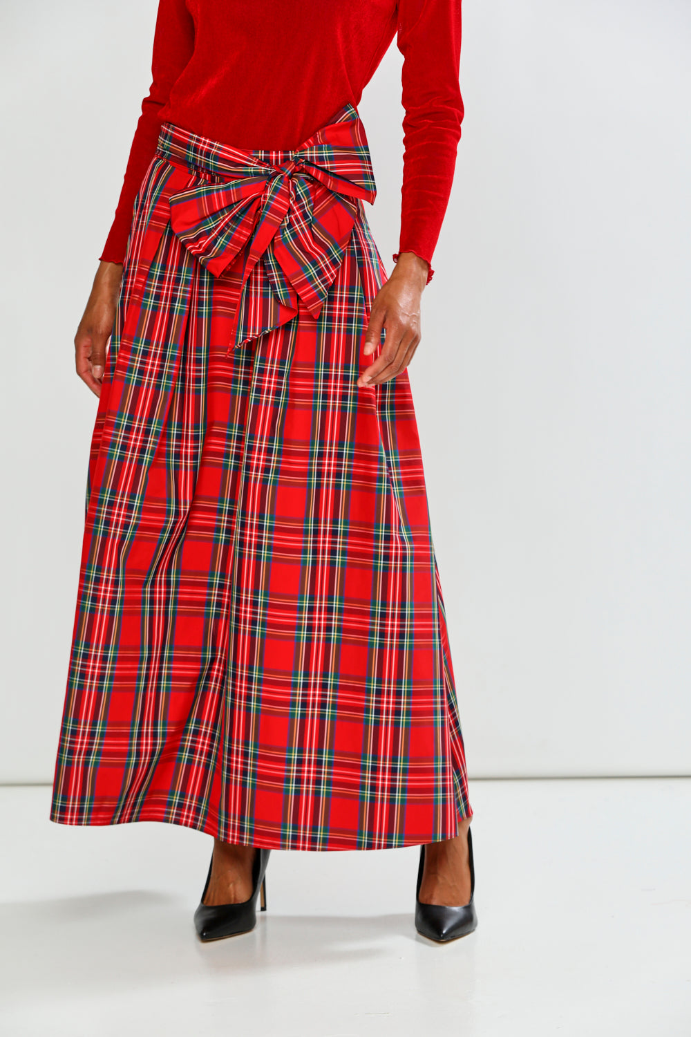 Person wearing a red plaid skirt with a white background