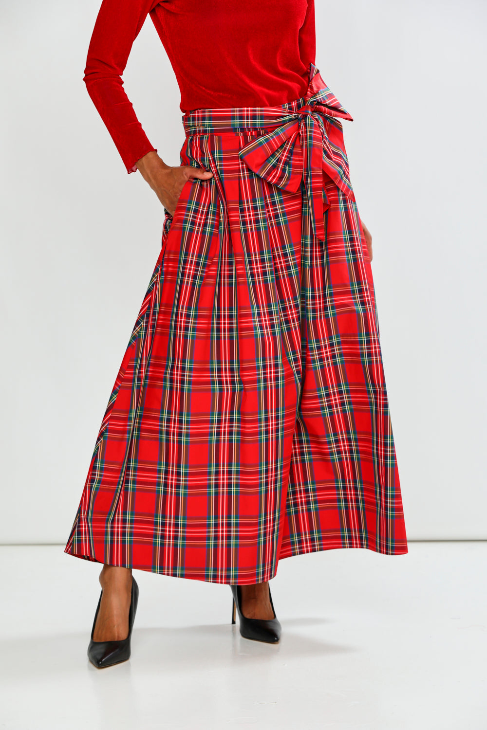 Person wearing a red plaid skirt with a white background