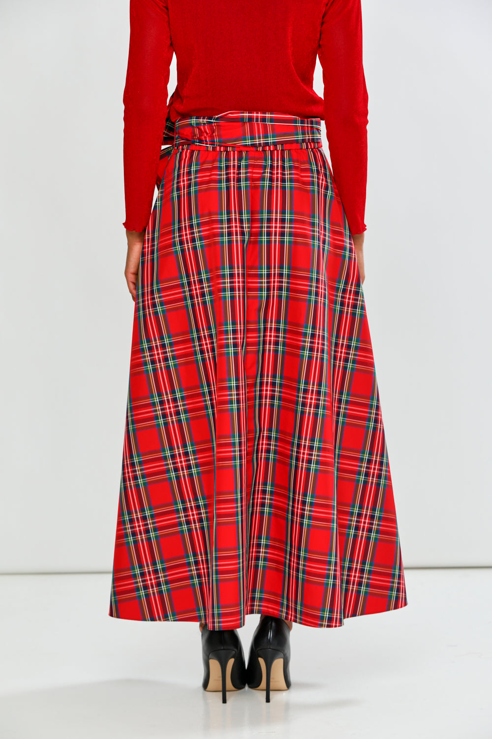 Person wearing a red plaid skirt with a white background