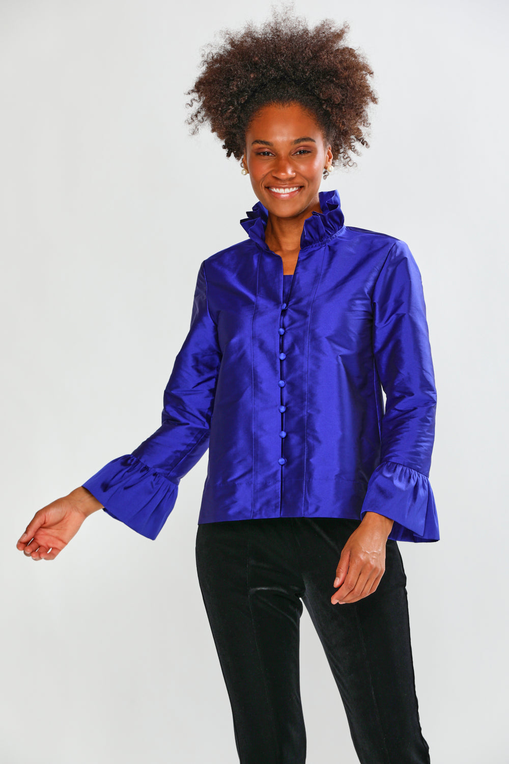Woman wearing a blue taffeta blouse with black pants on a white background