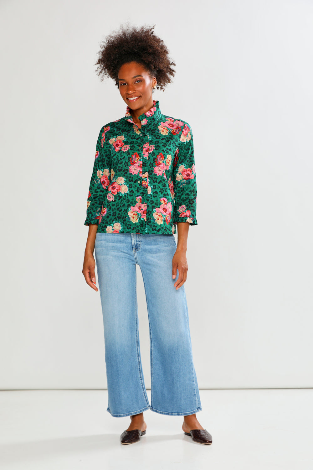 Woman wearing a floral blouse and jeans on a white background