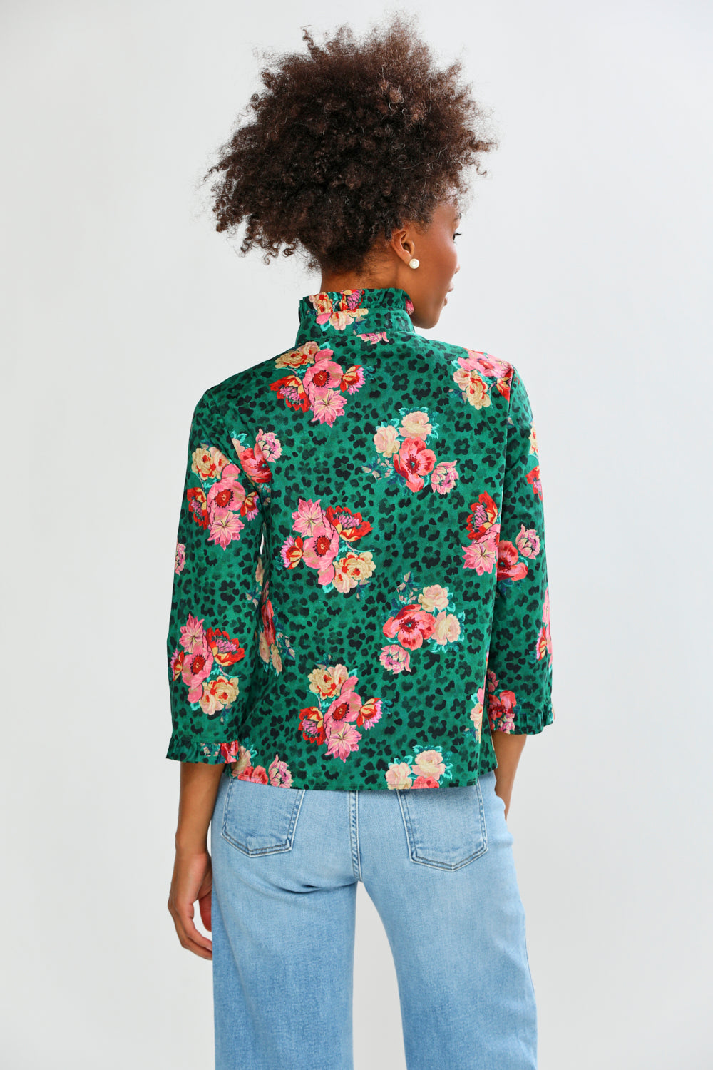 Person wearing a floral patterned shirt with a plain background