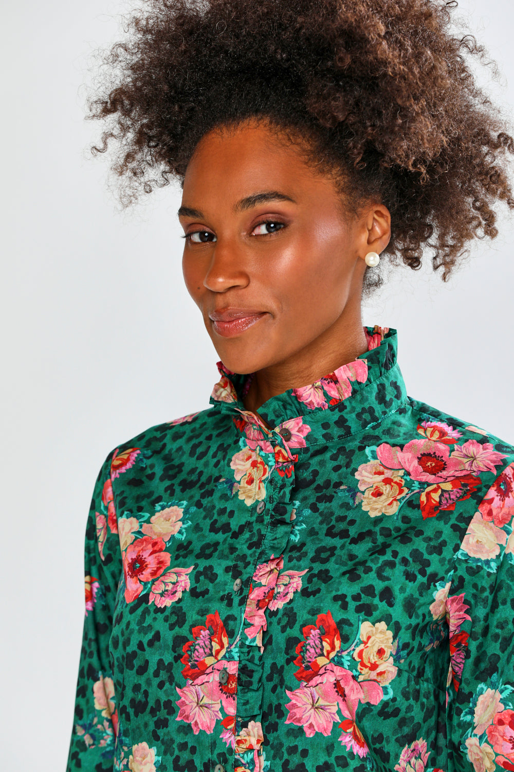 Woman wearing a green floral blouse with a white background