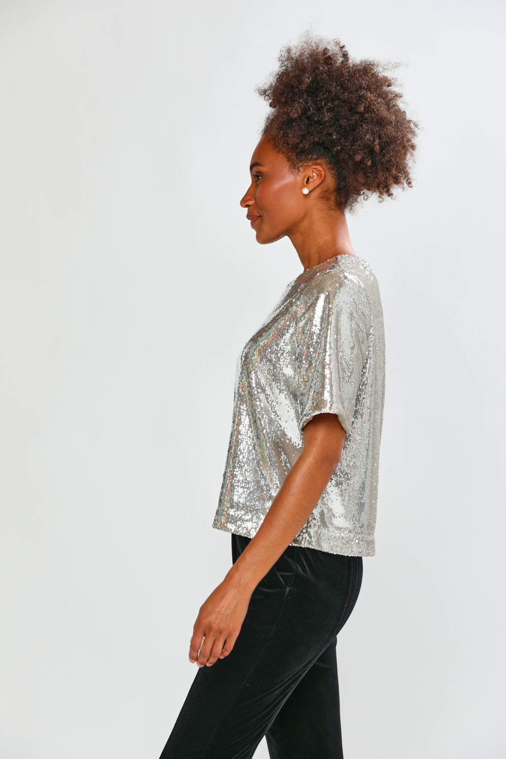 Woman wearing a silver sequin top against a white background