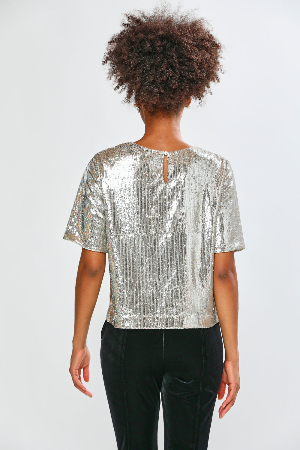 Person wearing a silver sequin top on a white background
