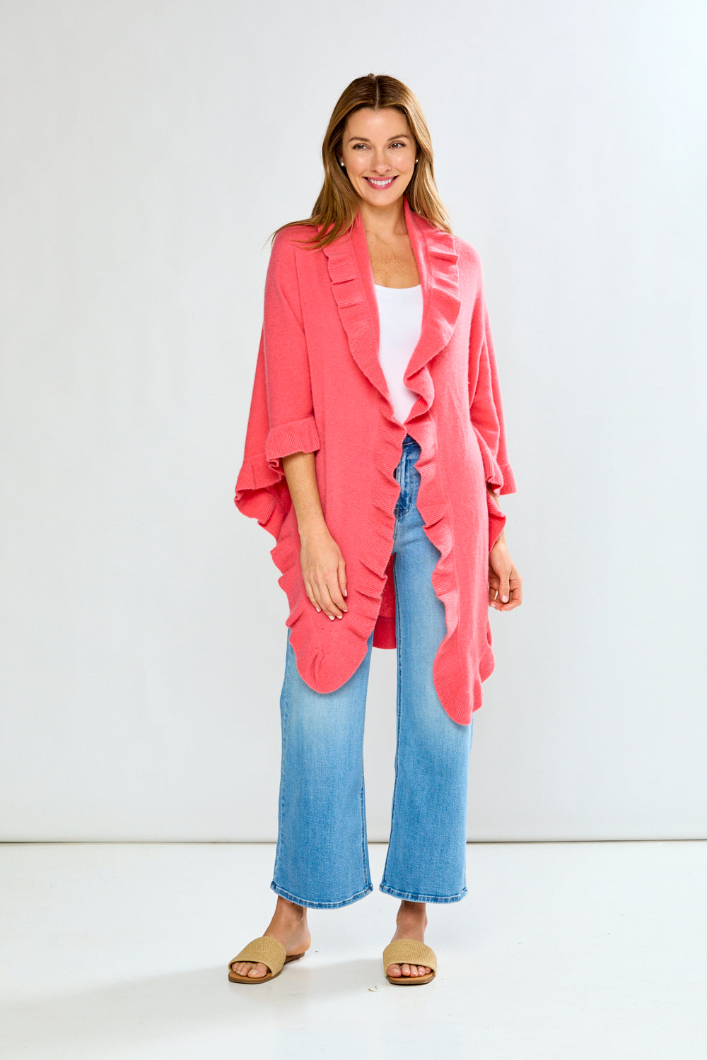 Woman wearing a pink jacket over a white top and blue jeans on a white background