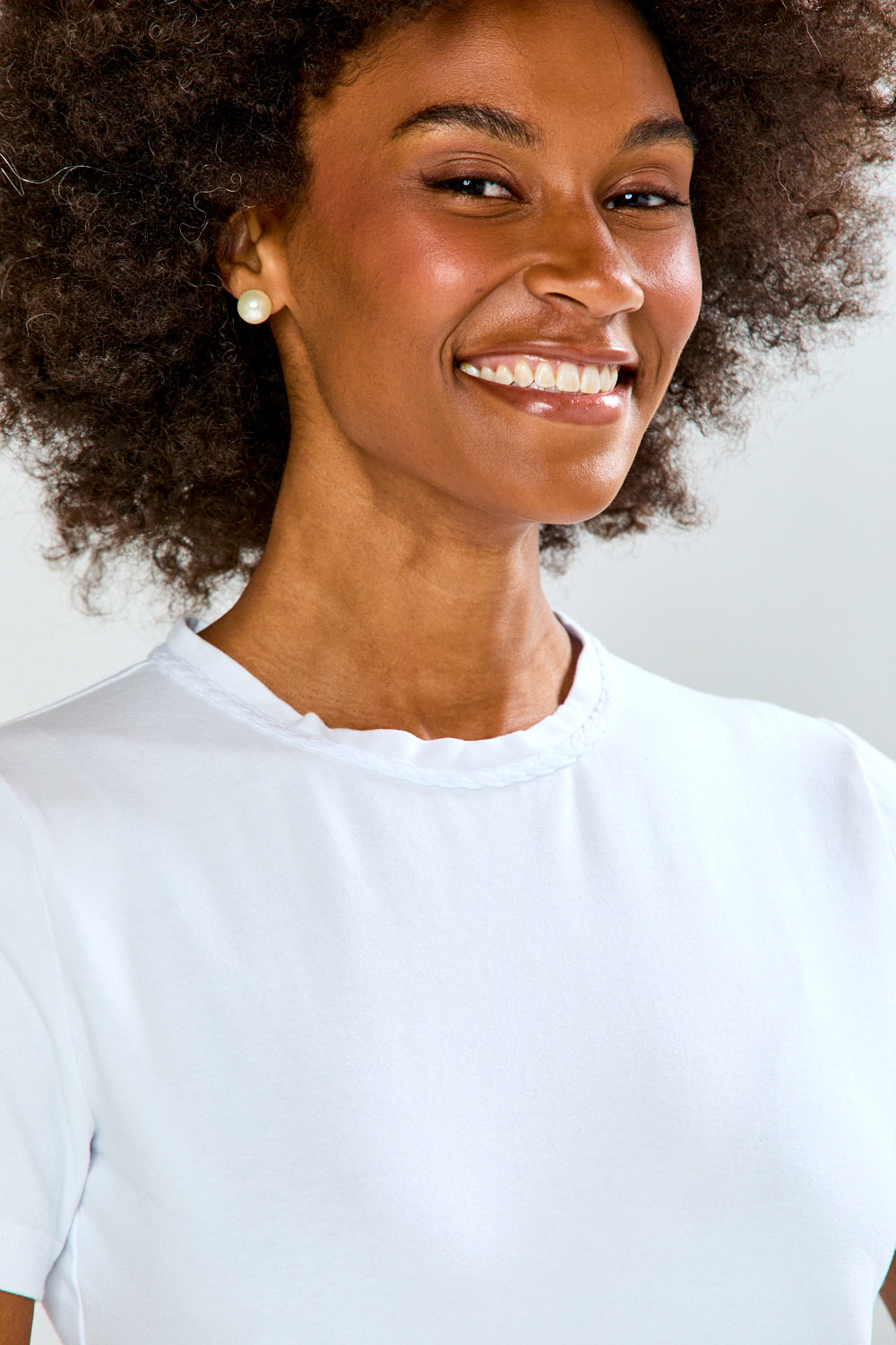Woman wearing a white t-shirt against a plain background