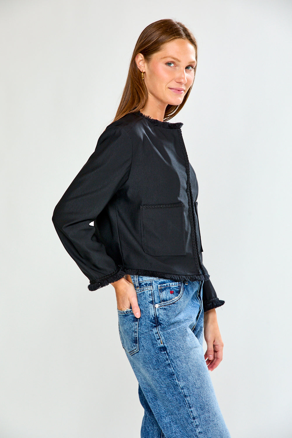 Woman wearing a black jacket and blue jeans on a white background