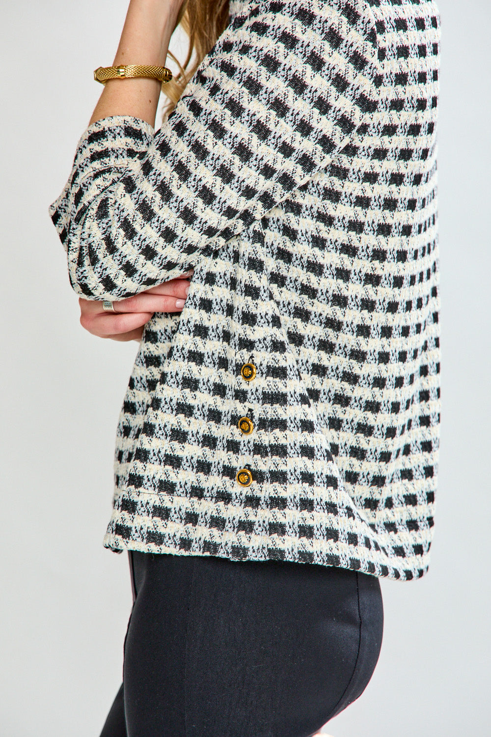 Woman wearing a black and white checkered blouse against a plain background