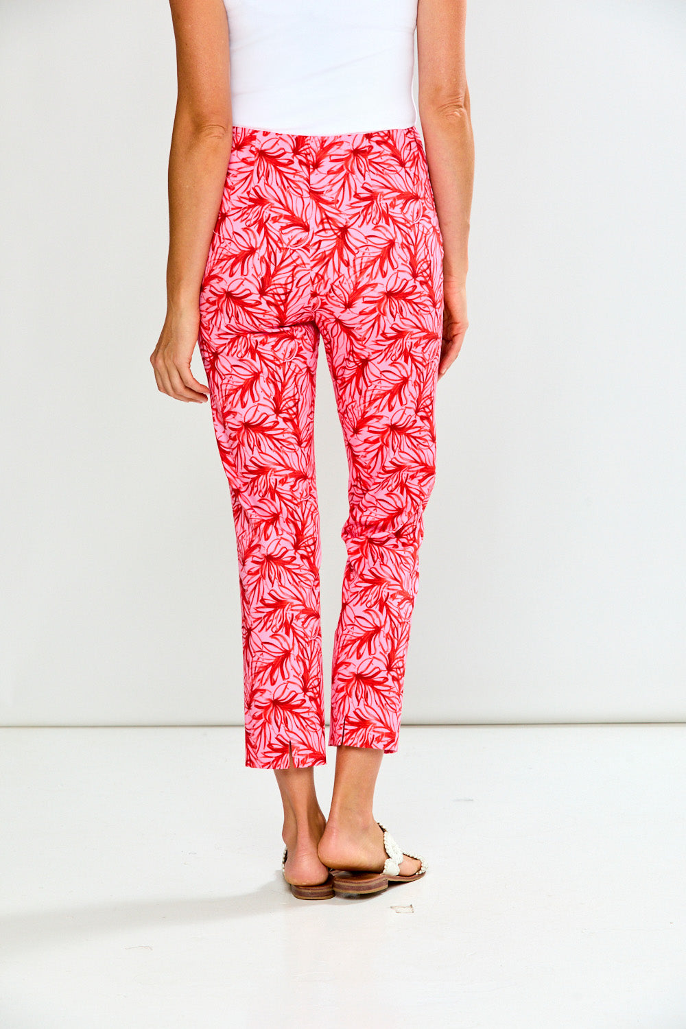 Person wearing pink leaf-patterned pants on a white background