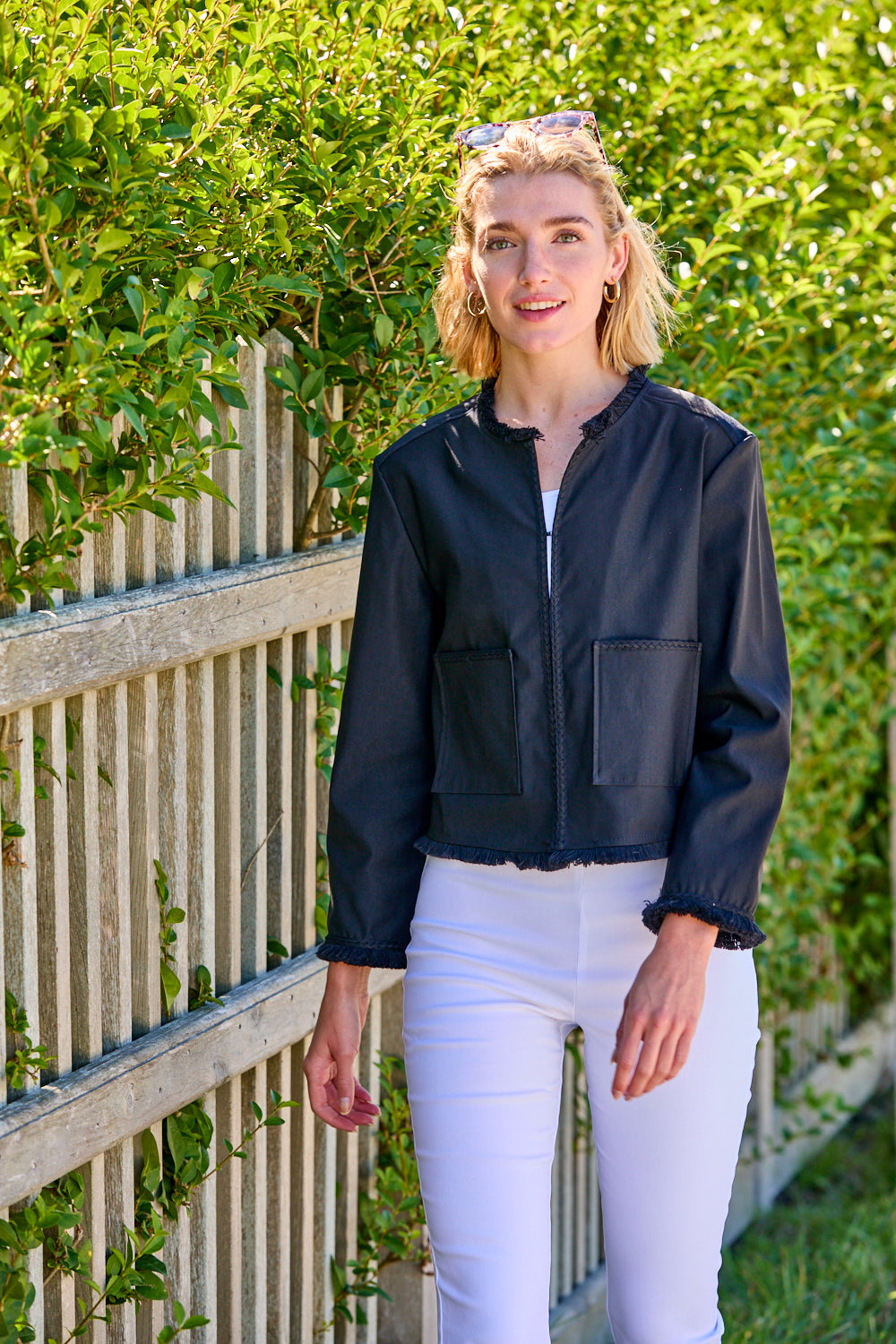 Woman wearing a black jacket with fringe detail and white pants