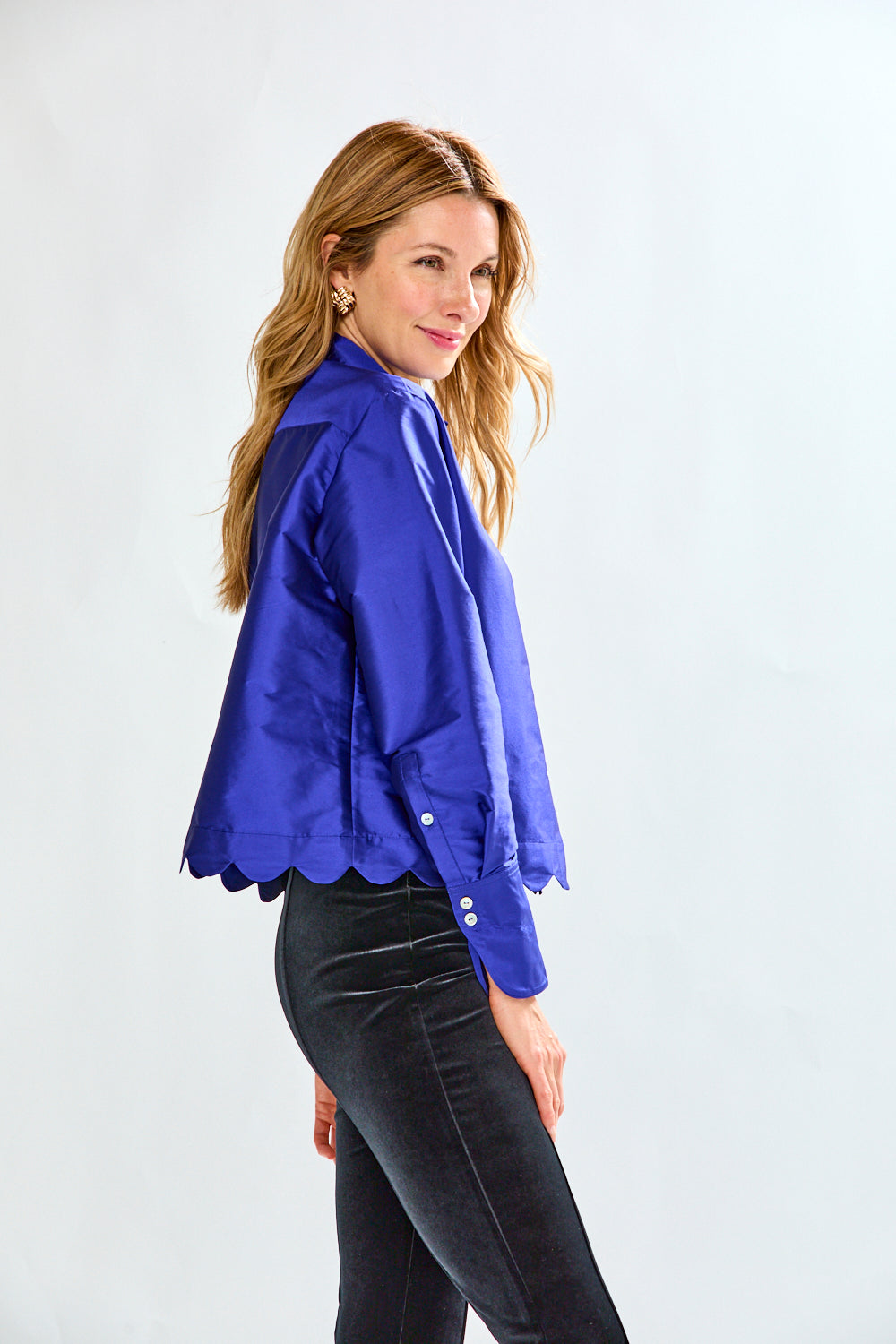 Woman wearing a blue blouse and black pants on a white background