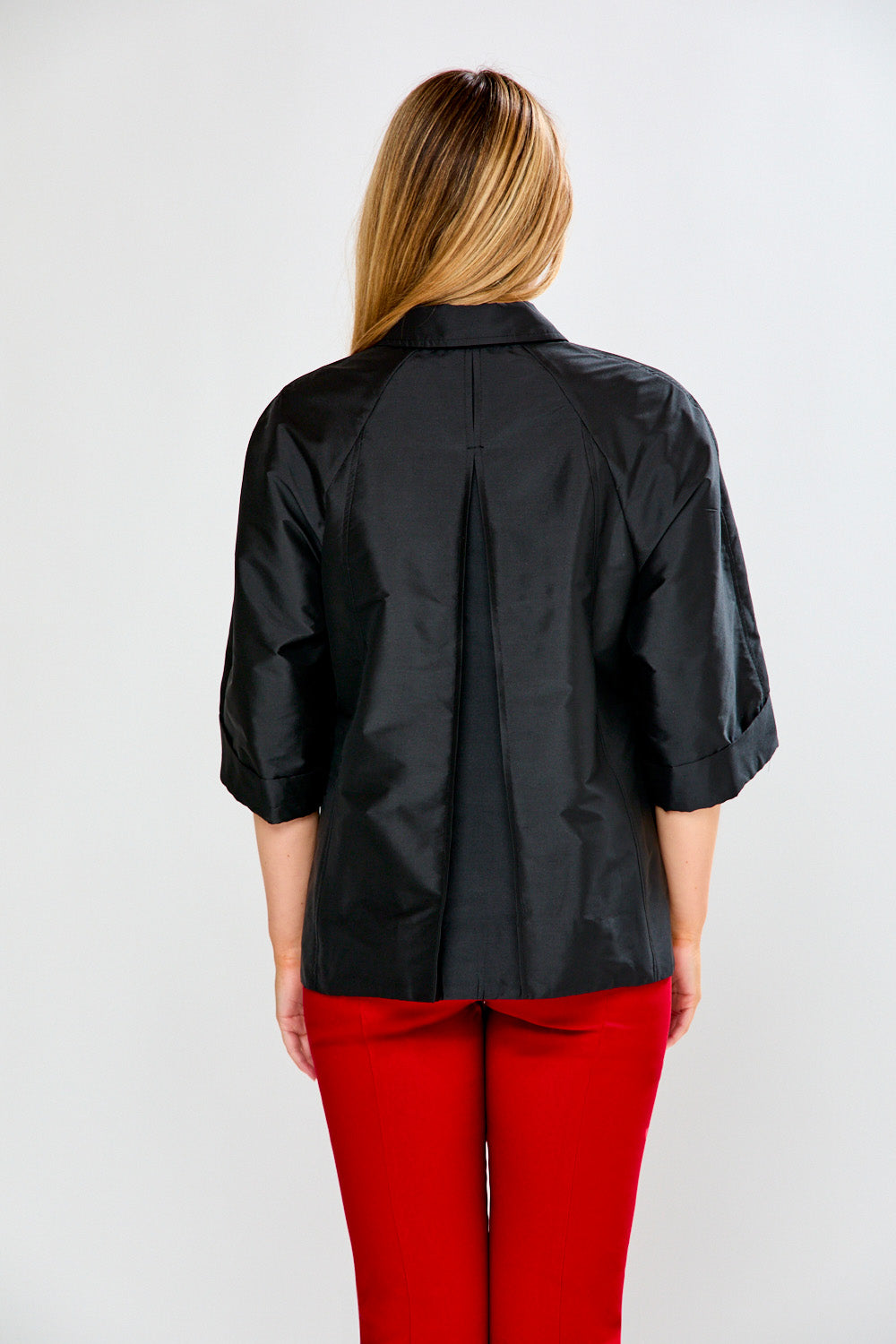 Person wearing a black jacket and red pants on a white background
