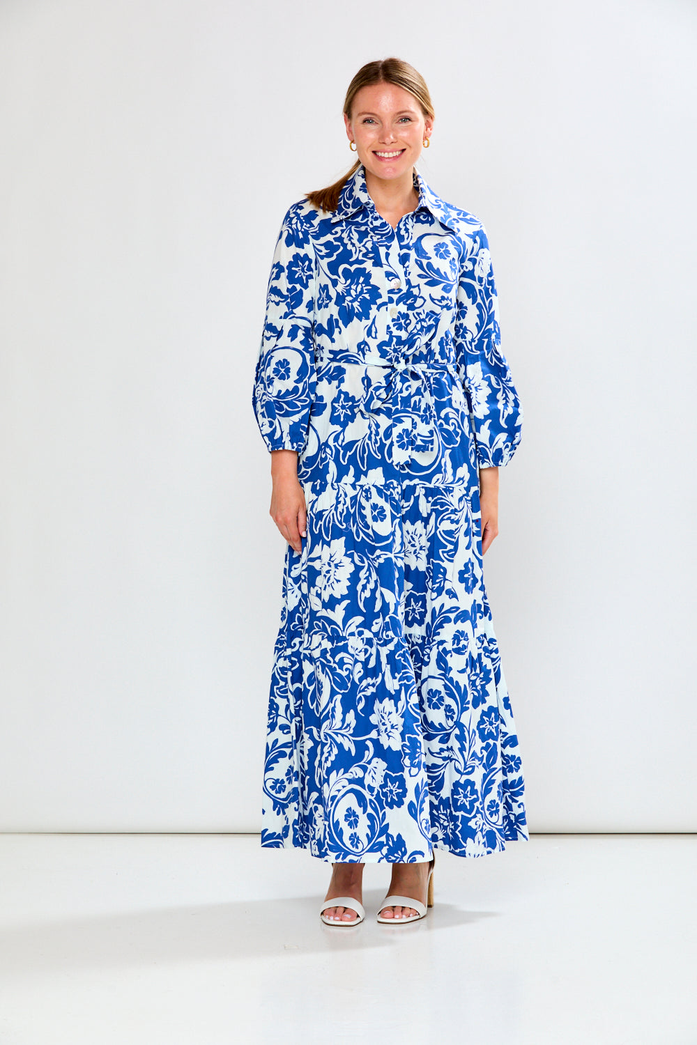Woman wearing a blue floral dress against a white background