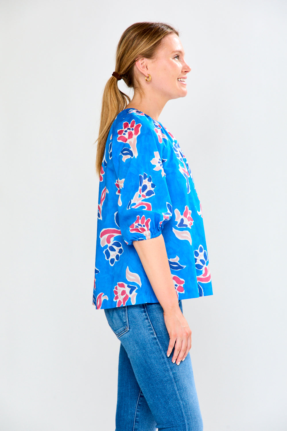 Woman wearing a blue floral blouse and jeans on a white background
