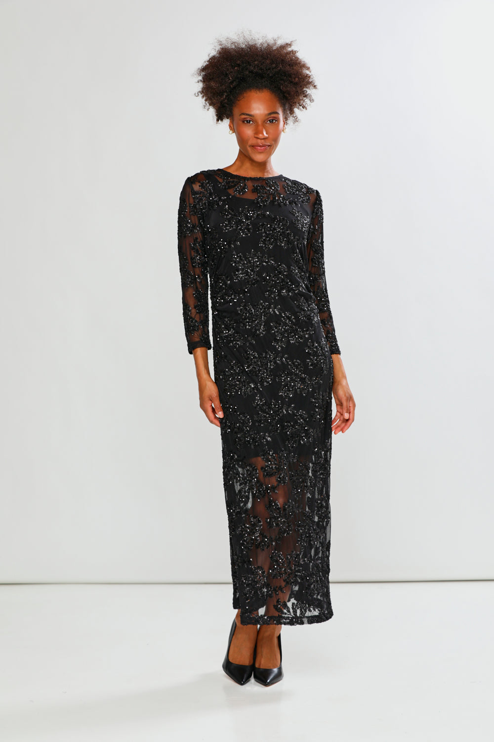 Woman wearing a black sequin dress against a white background