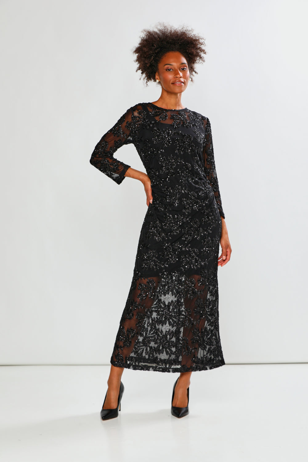 Woman wearing a black sequin dress against a white background
