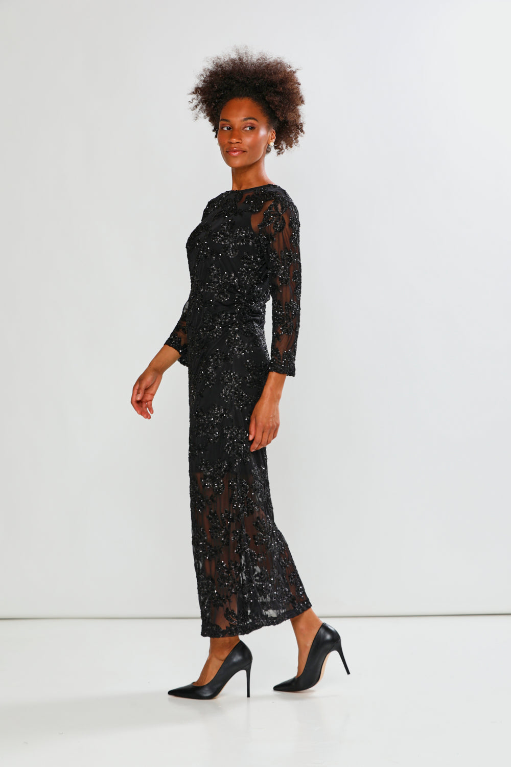 Woman wearing a black sequin dress against a white background