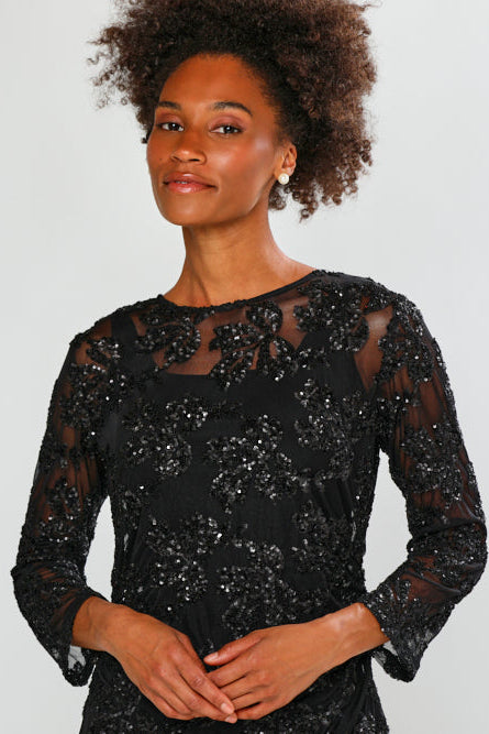 Woman wearing a black sequin dress against a white background