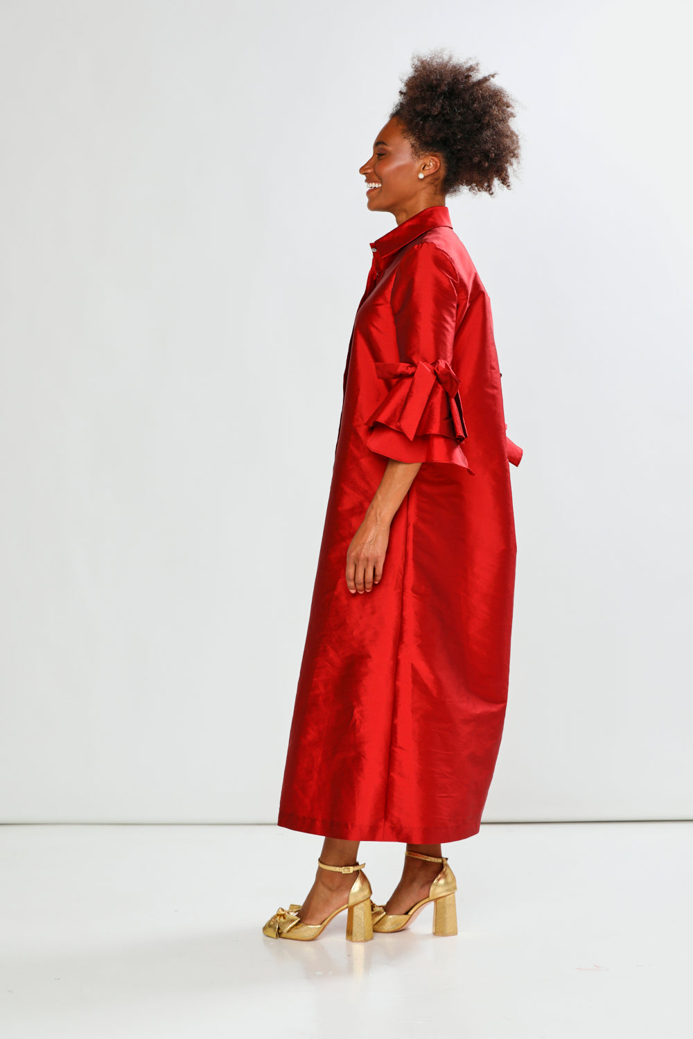Woman wearing a red dress with a bow detail on a white background