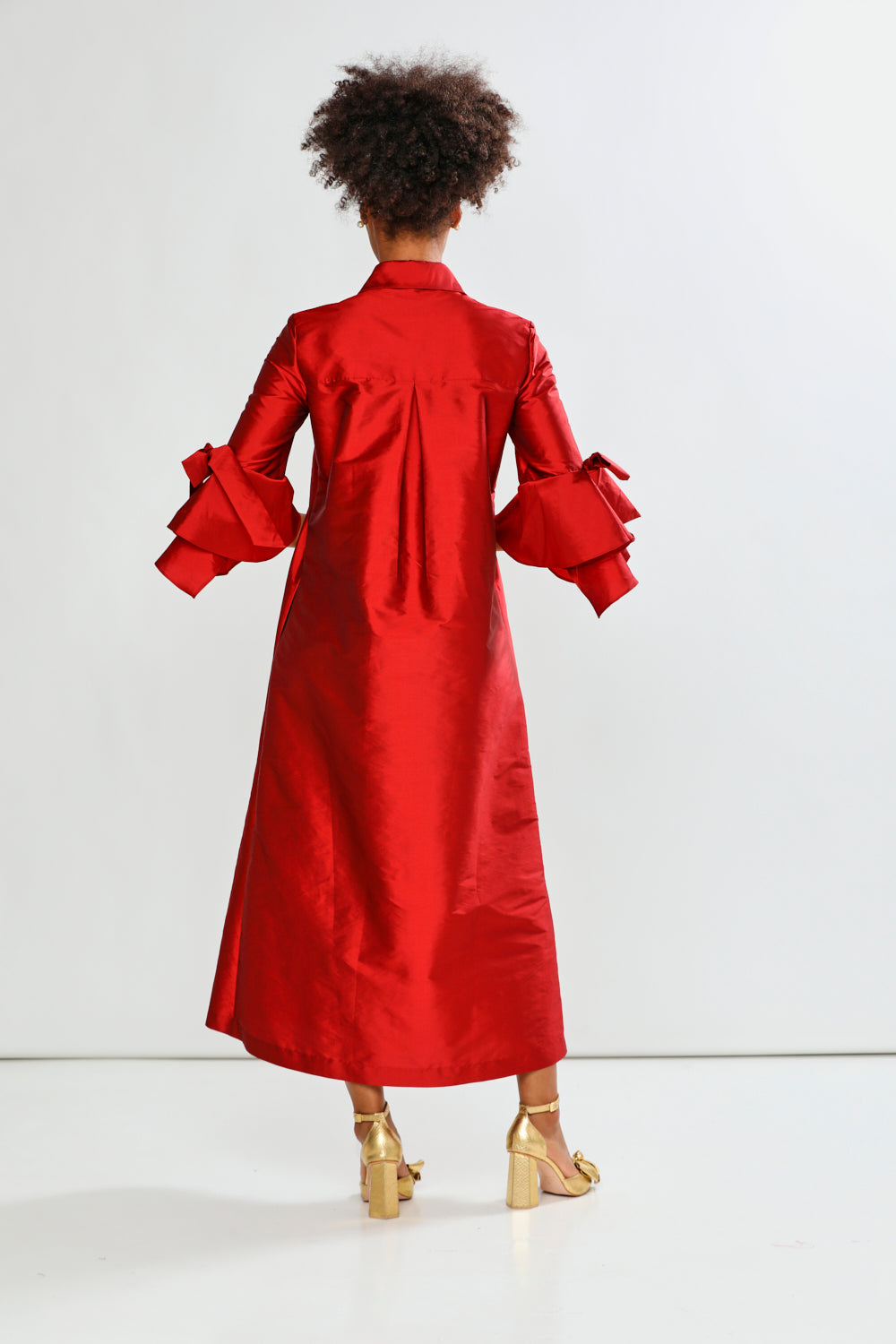 Person wearing a red dress with ruffled sleeves on a white background