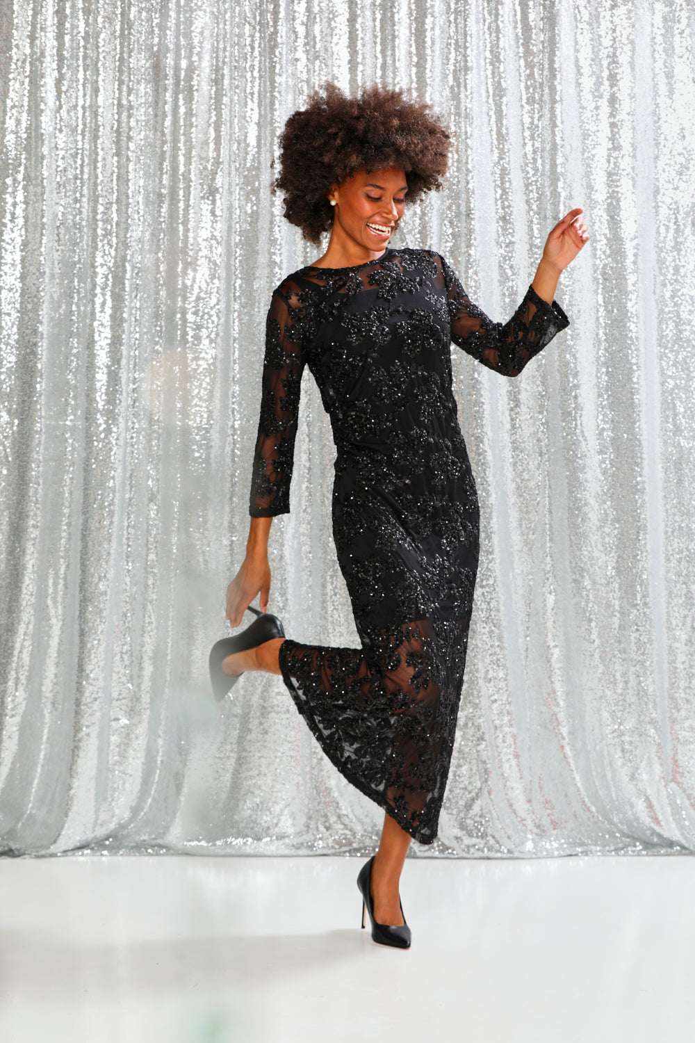 Woman wearing a black sequin dress against a white background