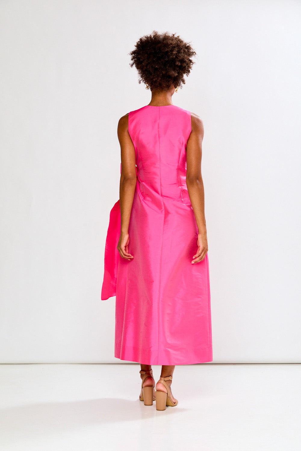 Person wearing a bright pink sleeveless dress against a white background