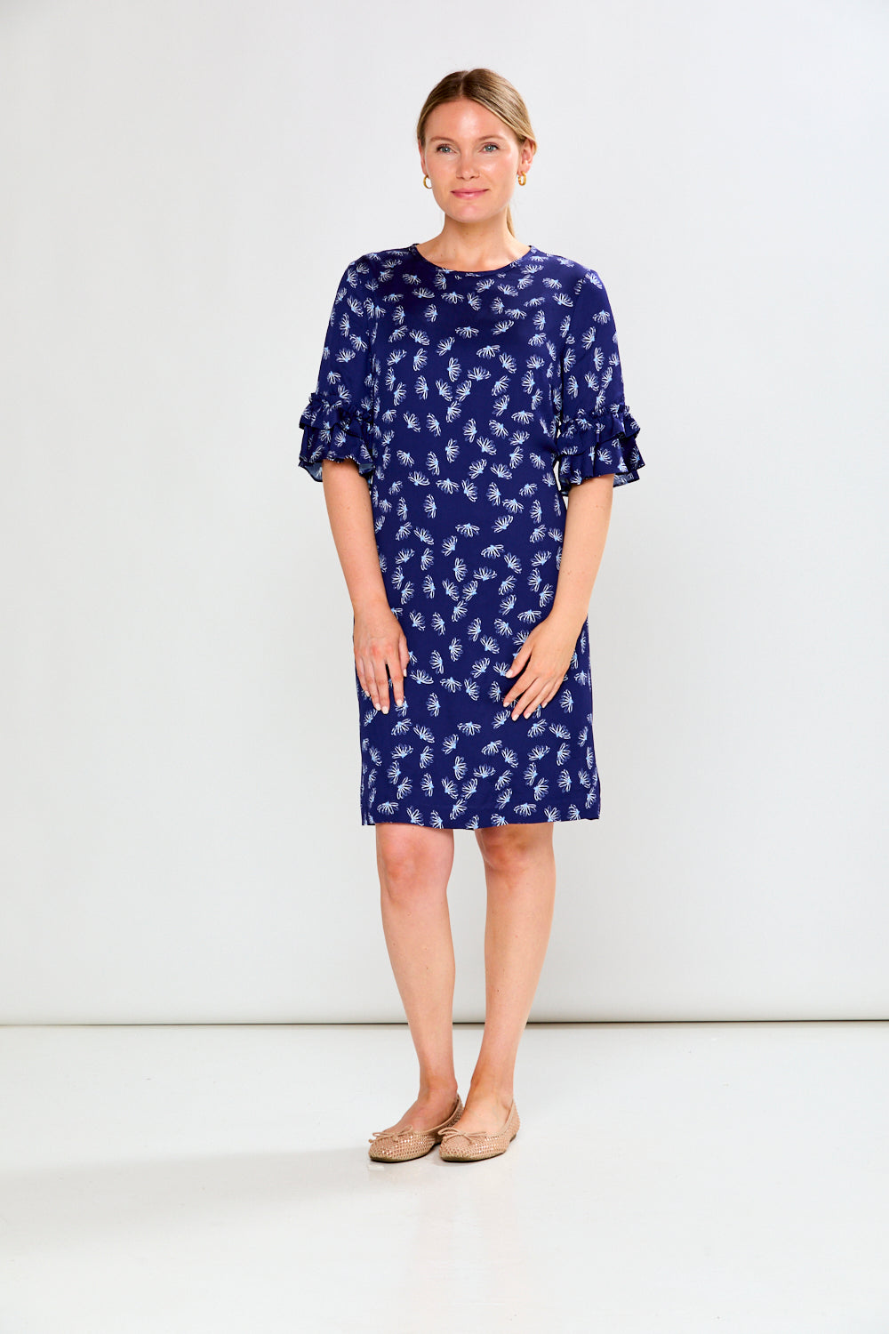 Woman wearing a blue dress with white floral pattern on a white background