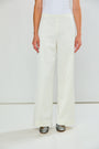 The Reyna Pant - Off White, wide leg women's pants modeled with a fitted white top and metallic pointed toe shoes in a minimalist studio setting
