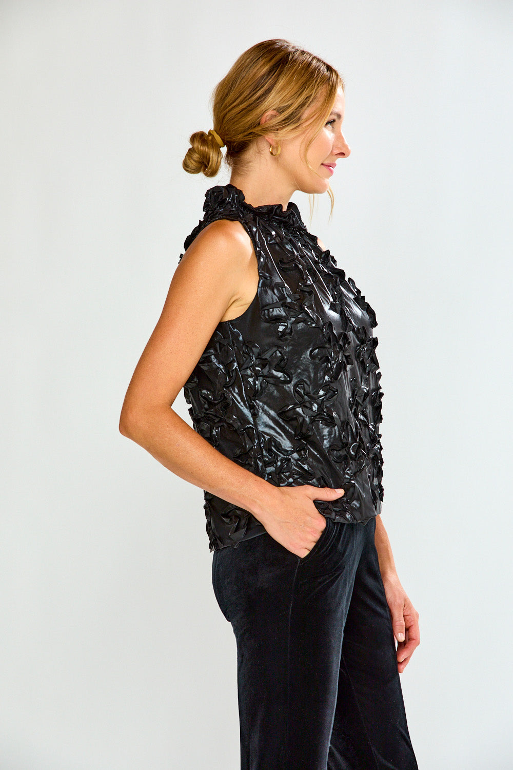 Woman wearing a black metallic top and black pants on a white background