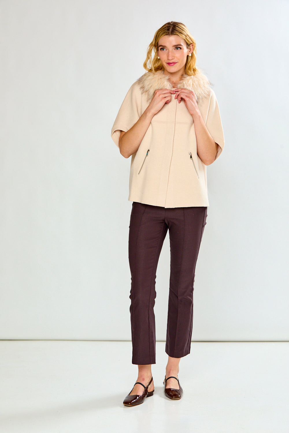 A person shown from the waist down wearing dark brown cropped flare pants and dark flat sandals against a clean white studio background.