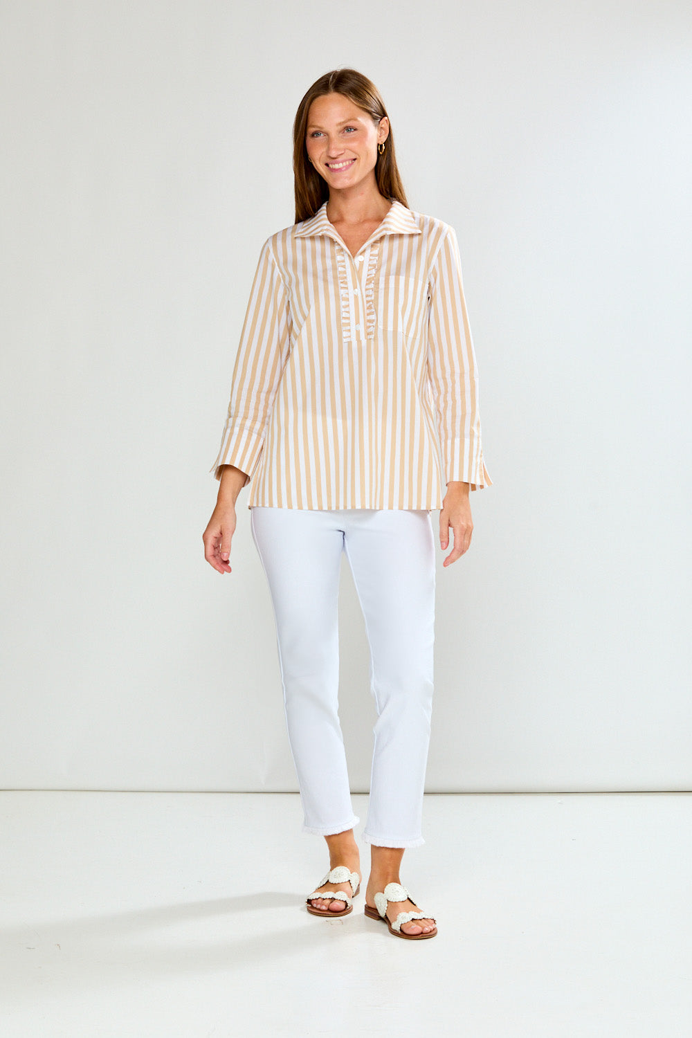 Woman wearing a striped shirt and white pants on a plain background