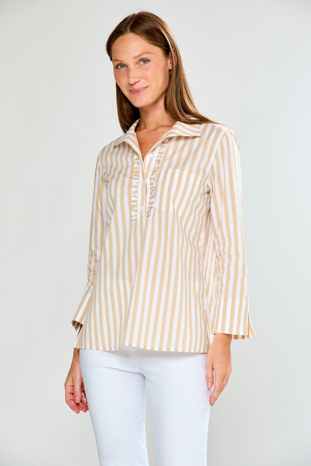 Woman wearing a striped shirt and white pants on a plain background